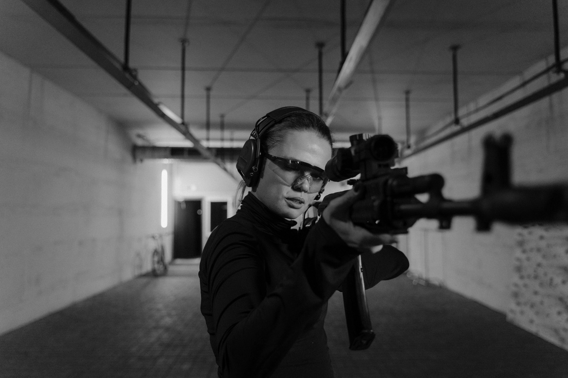 Woman Holding a Black Rifle Aiming for the Target